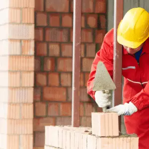 Murer arbejder med at lægge mursten på en facade som en del af professionelt murarbejde